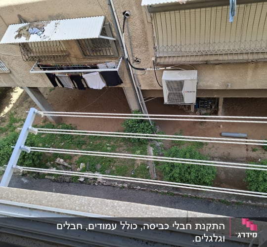 חבלי כביסה עם בגדים תלויים ליד מזגן